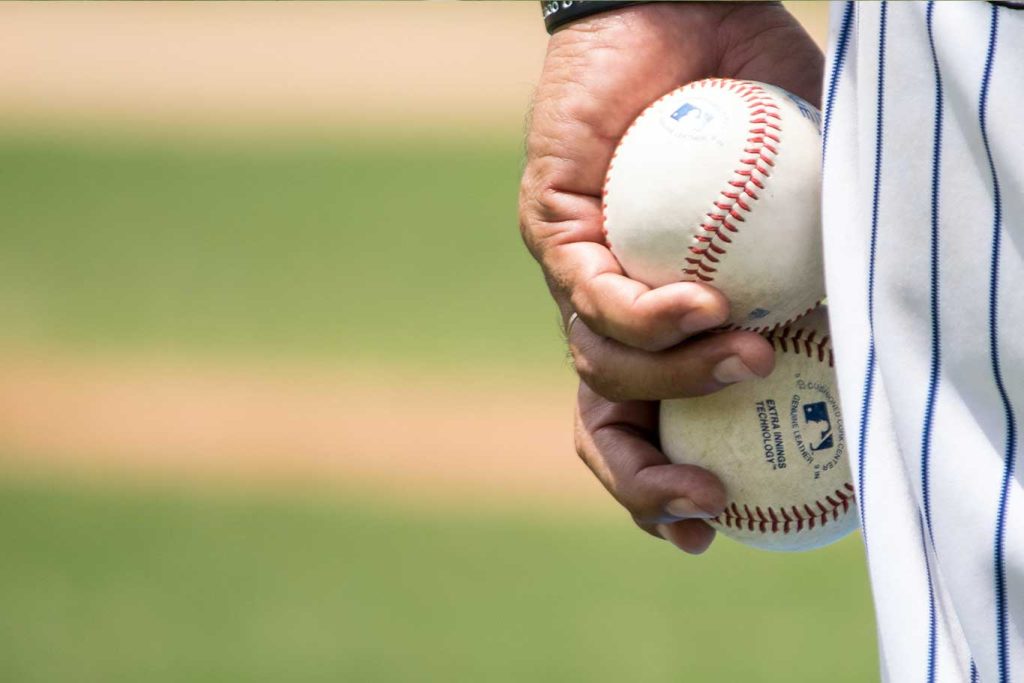 Baseball pitcher holding two baseballs